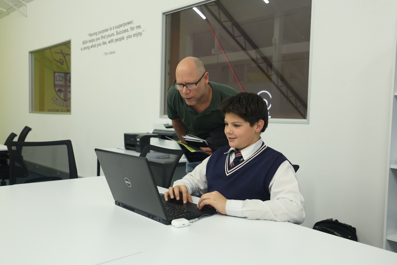 A learning coach supporting a learner using a laptop at BGA